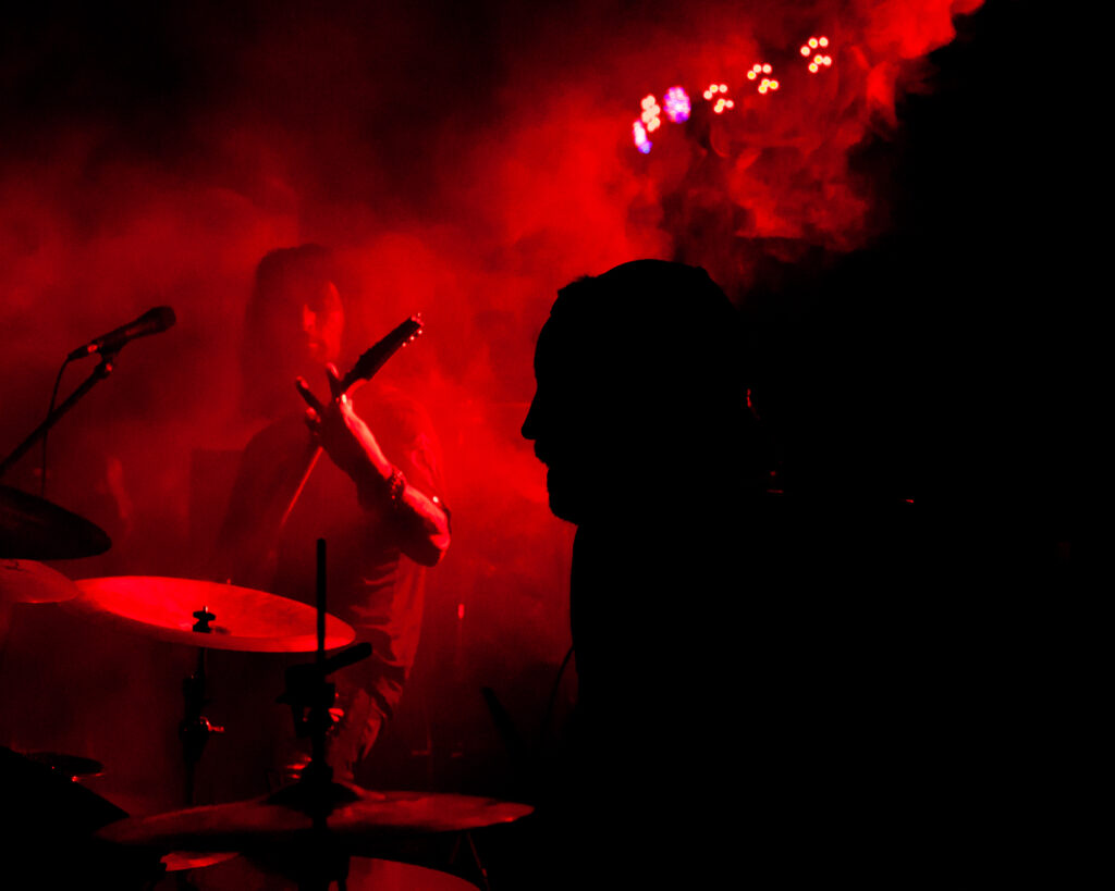 concert photography mood shot of metal band Nightmare Empire drummer in black sillouhette with red fog at The Vortex in Arkon